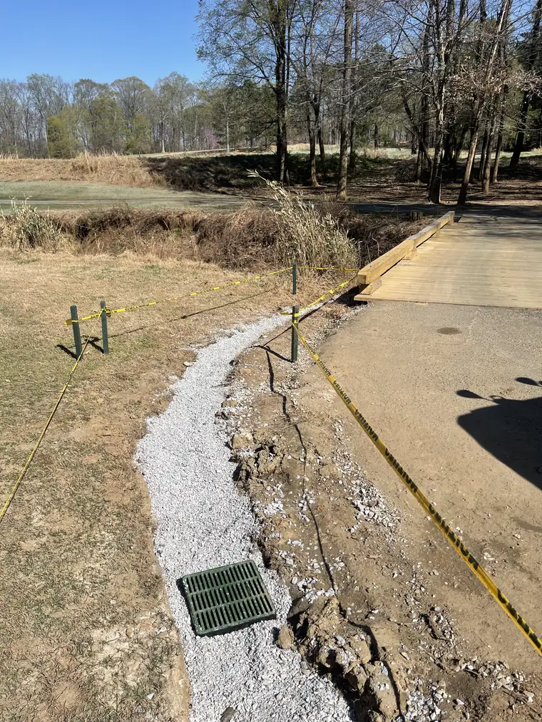 Gravel French drain and catch basin installed along a golf course cart path