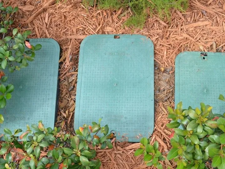 Green valve boxes set flush in a landscaped bed