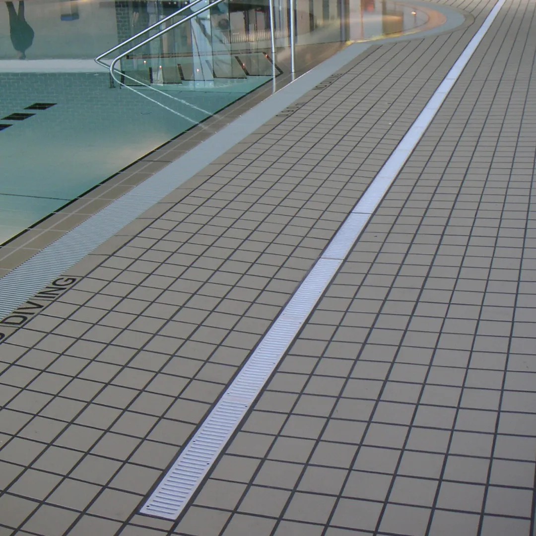 NDS Spee-D channel drain installed along a concrete pool deck, collecting splash-out at the deck edge